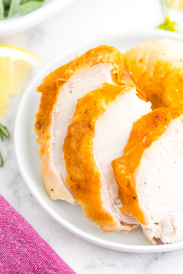 Thick slices of roast turkey on a white serving platter.