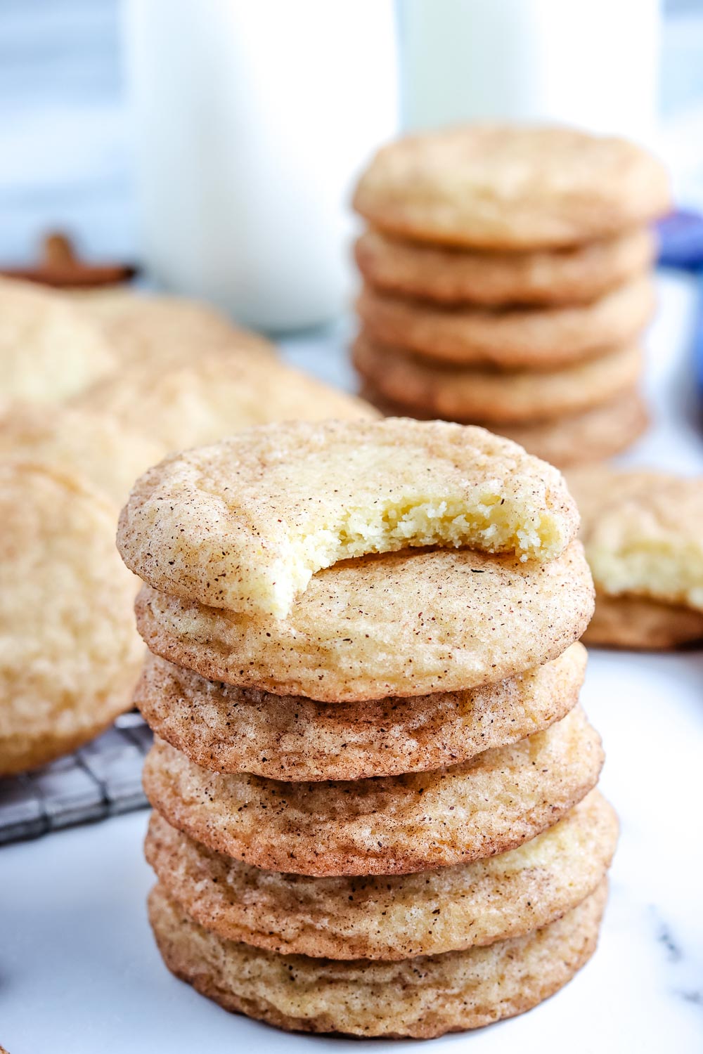 Six Snickerdoodle Cookies stacked on top of each other. The top one has a bite taken out of it. 