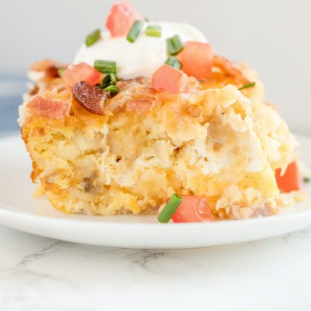 A close up picture of a piece of the Tater Tot Breakfast Casserole on a white plate.