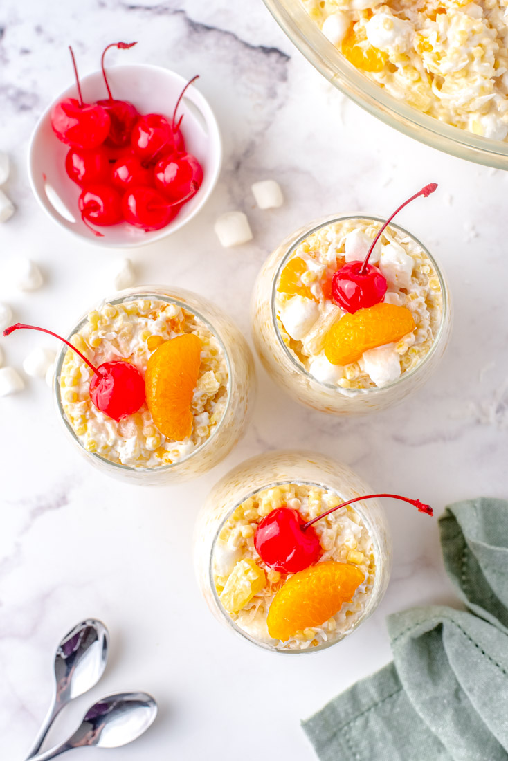 The finished Frog Eye Salad desert in clear glasses garnished with cherries and oranges.