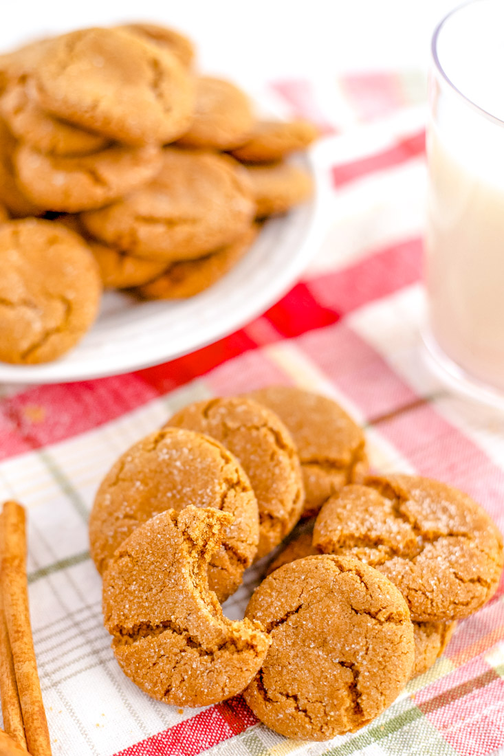 A pile of gingersnap cookies, one with a bite take out of it.