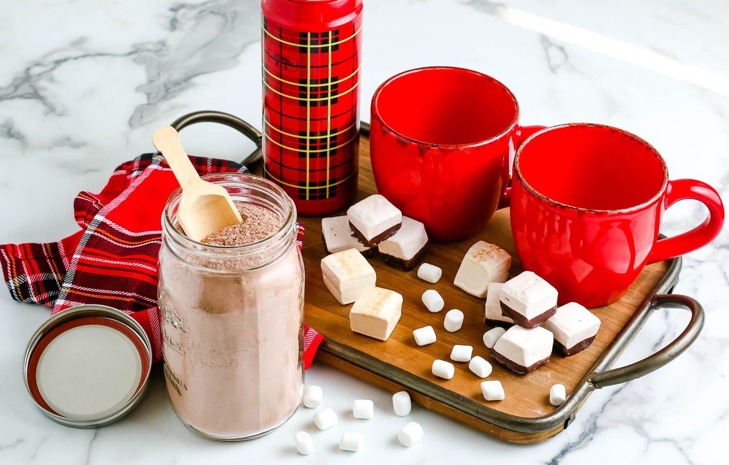 Homemade Hot Chocolate Mix on a table top with mugs and marshmallows.