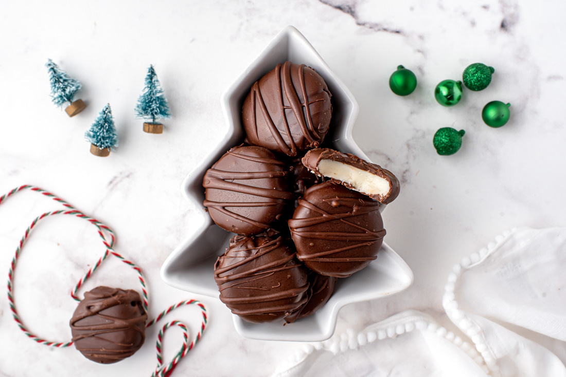 Homemade Peppermint patties in a candy dish with a bite taken out of one.