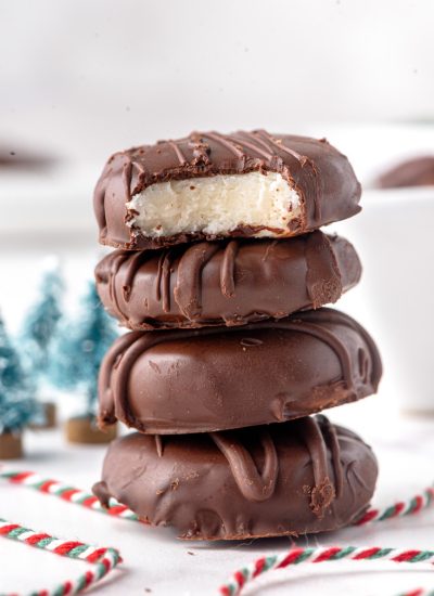 Four peppermint patty candies stacked on top of each other with bite taken out of the top one.