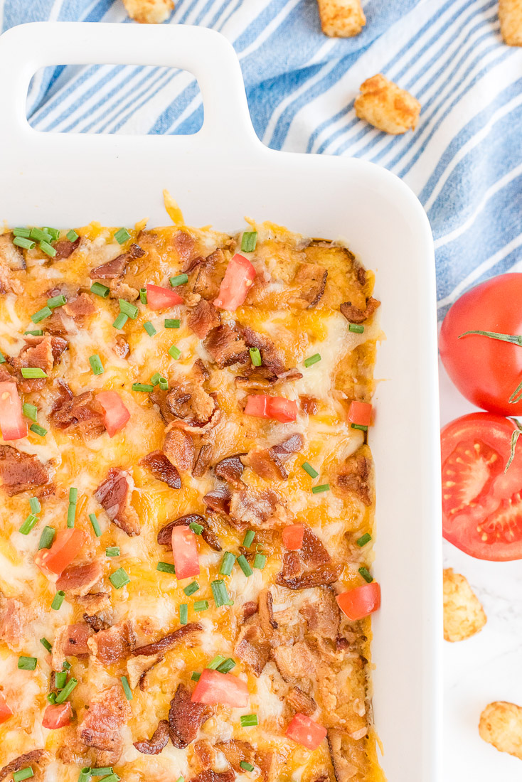 An overhead picture of the finished Tater Tot Breakfast Casserole garnished with tomatoes and green onion.