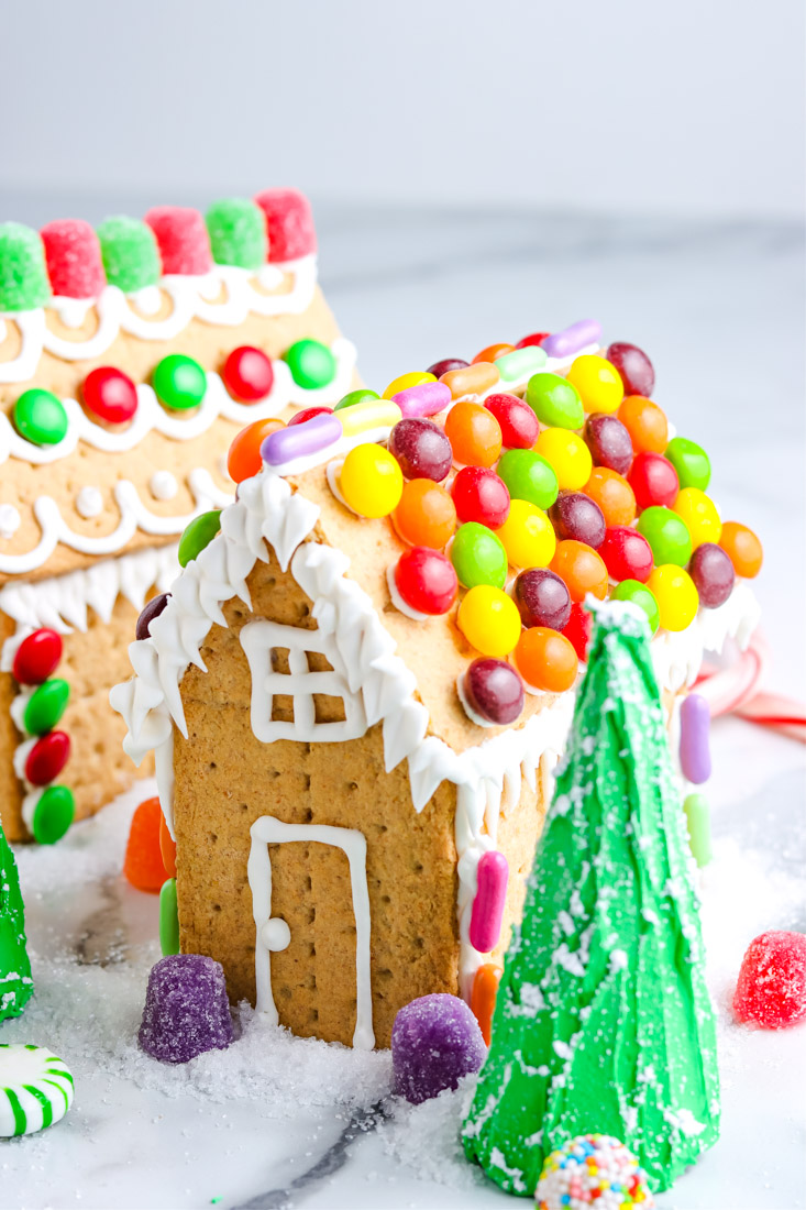 A close up picture of a Graham Cracker Gingerbread Houses decorated with royal icing and Skittles.