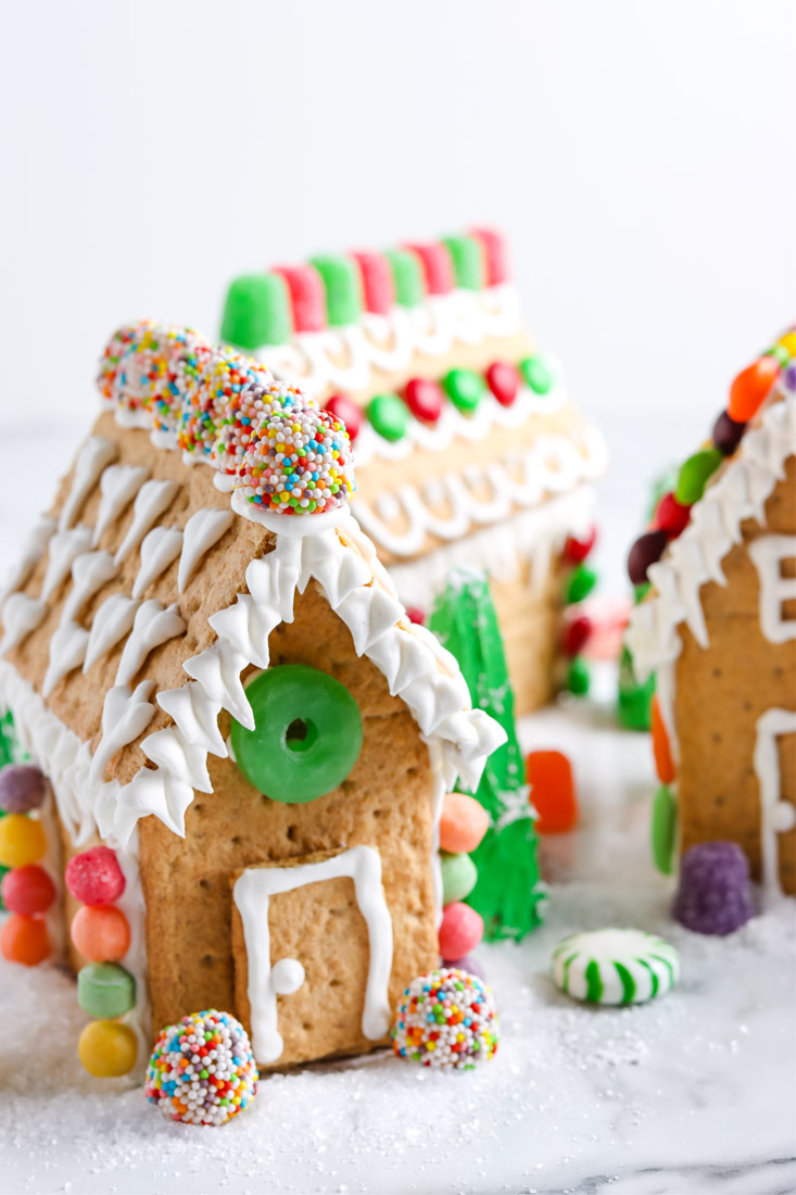 Three Graham Cracker Gingerbread Houses on a tabletop.