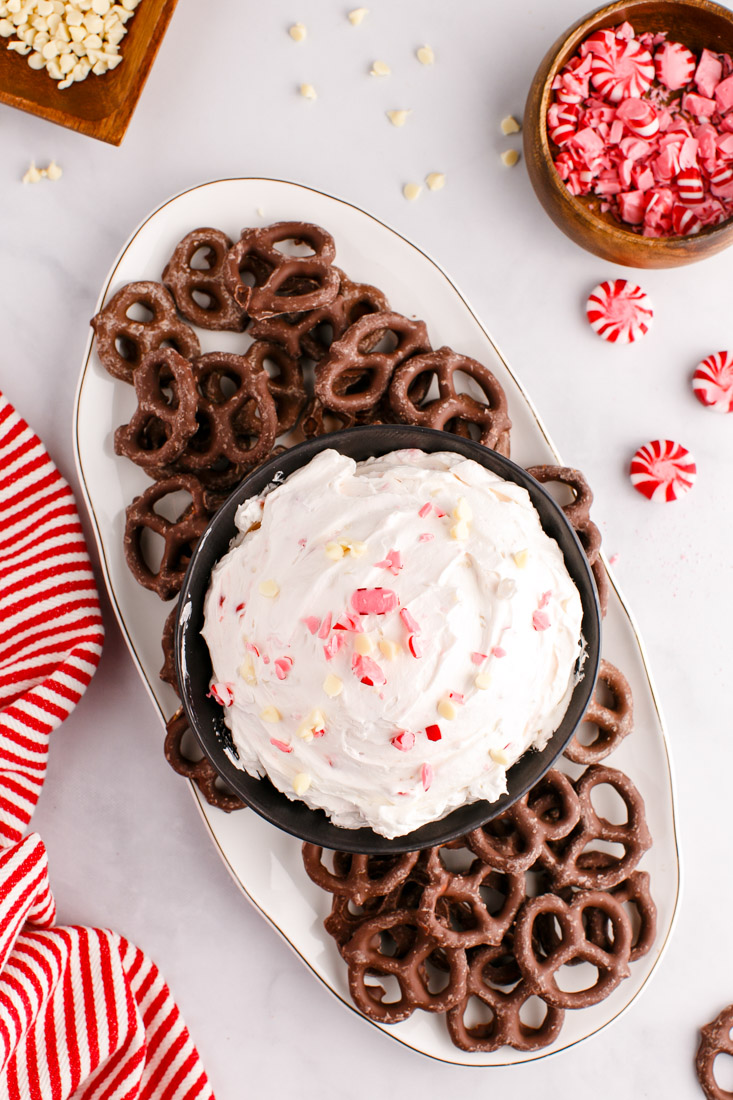 An overhead picture of the finished Peppermint Cheesecake Dip on a serving platter with chocolate covered pretzels.
