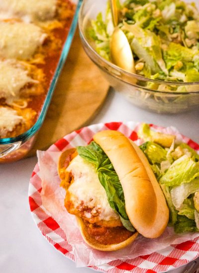 A finished Chicken Parmesan Sub on a plate with salad.