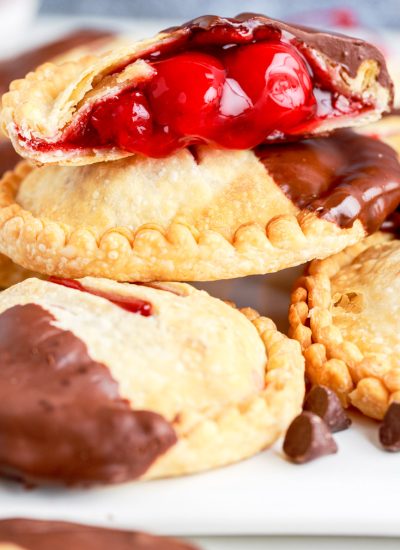A close up picture of a finished Air Fryer Cherry Hand Pies that has been cut into and dipped in chocolate.