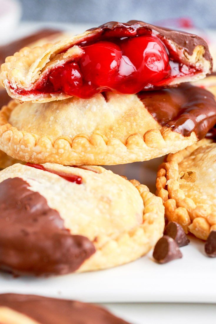 A close up picture of a finished Air Fryer Cherry Hand Pies that has been cut into and dipped in chocolate. 