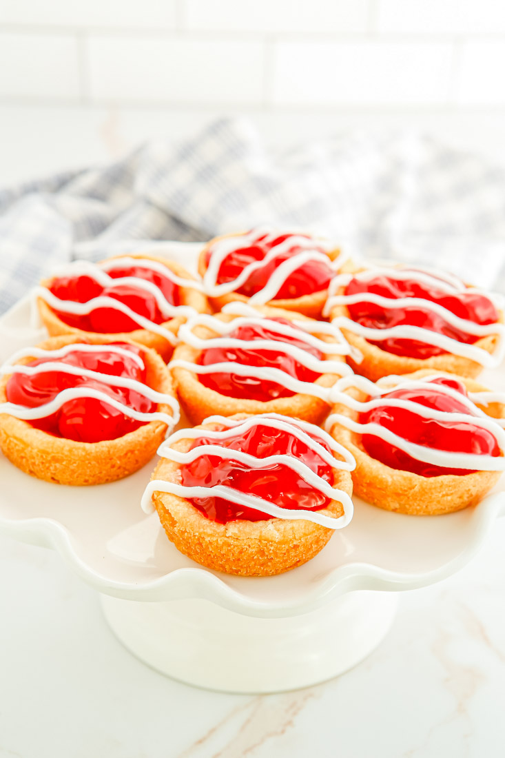 Seven Cherry Pie Cookies on a white cake stand.