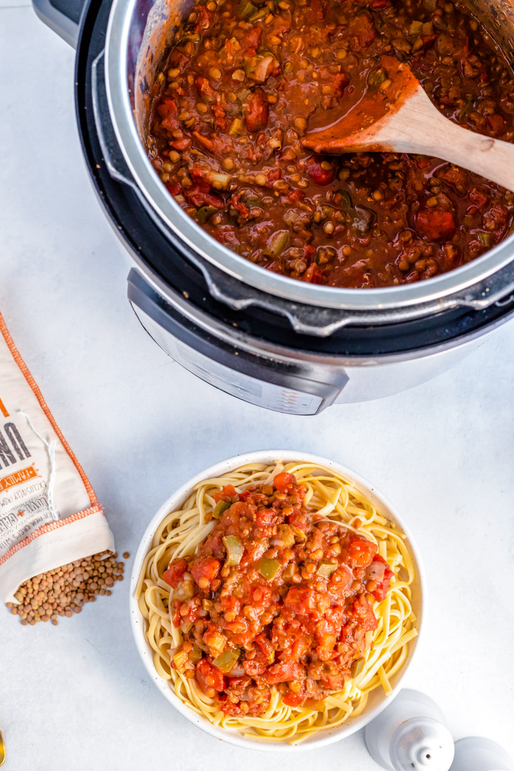 An overhead picture of the finished Instant Pot Lentil Bolognese in an Instant pot and over some cooked pasta.