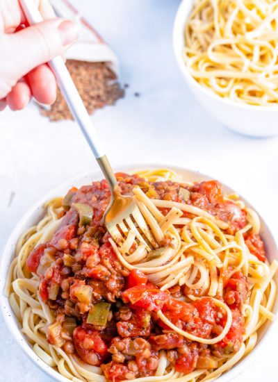 A fork twirling pasta covered in Instant Pot Lentil Bolognese.