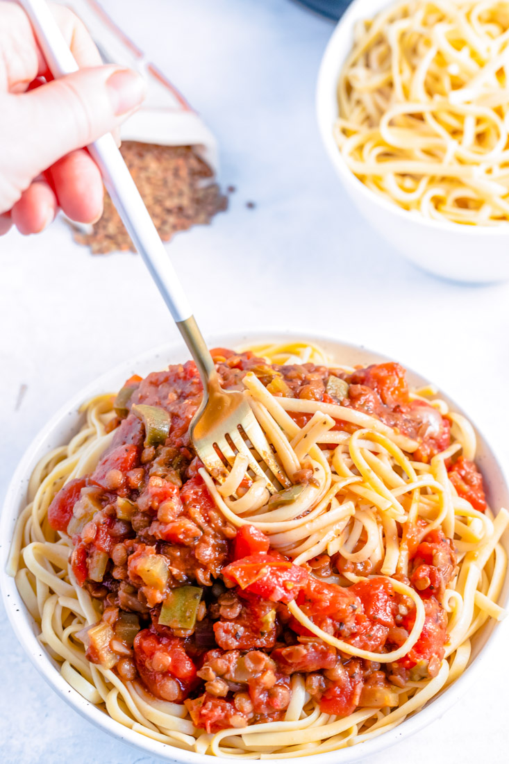 A fork twirling pasta covered in Instant Pot Lentil Bolognese.