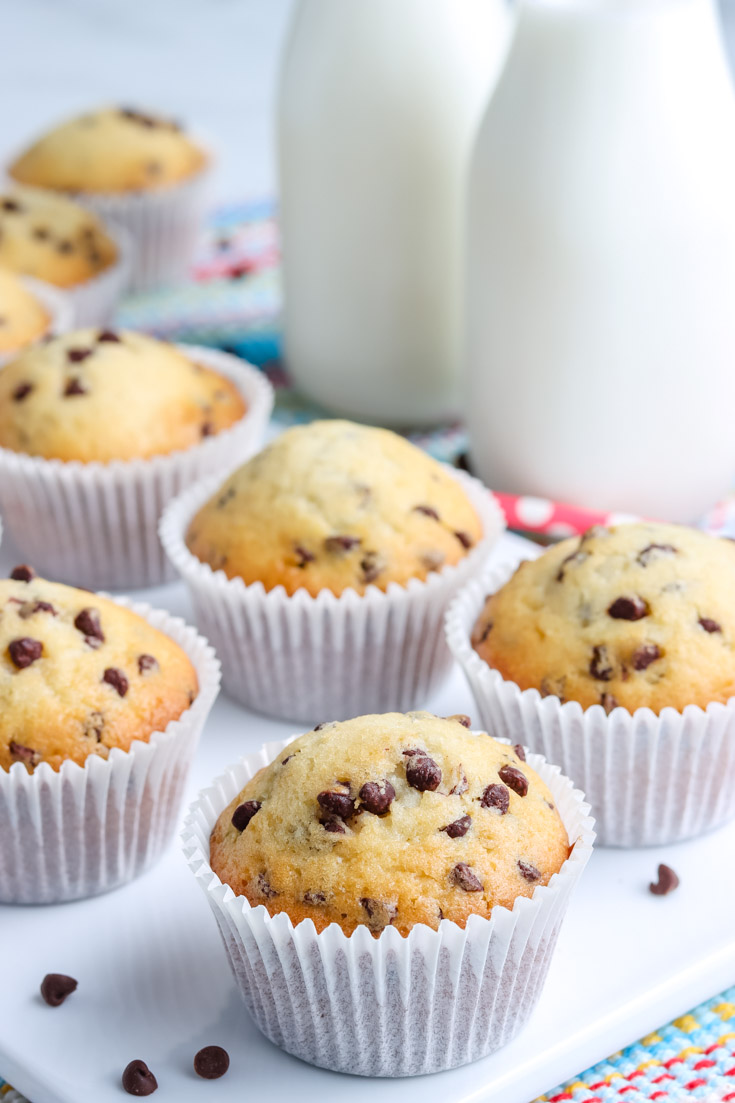 The finished Chocolate Chip Muffins on a white platter with milk in the background.