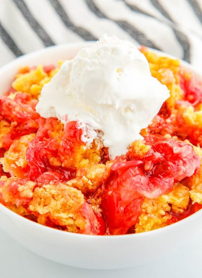 Cherry Pineapple Dump Cake in a bowl with some vanilla ice cream.