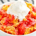 A close up picture of the finished Cherry Pineapple Dump Cake in a white bowl with some ice cream.