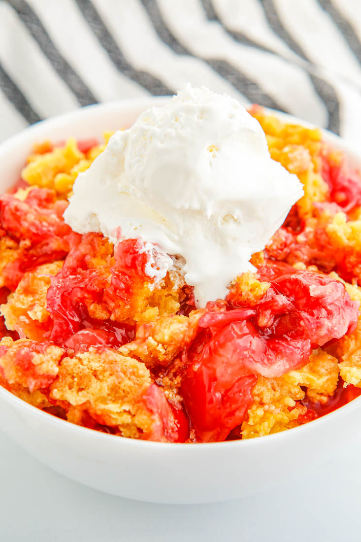 Cherry Pineapple Dump Cake in a bowl with some vanilla ice cream.