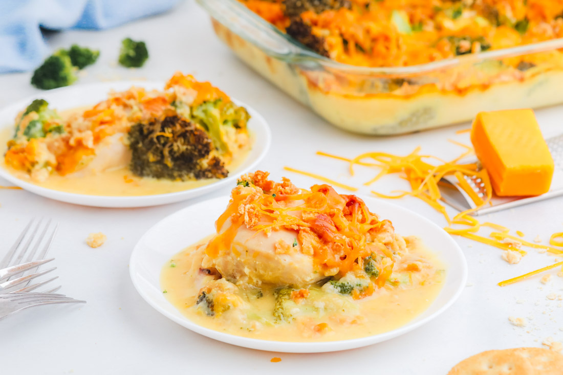 The finished Cracker Barrel Broccoli Cheddar Chicken on a white plate and in a casserole dish.