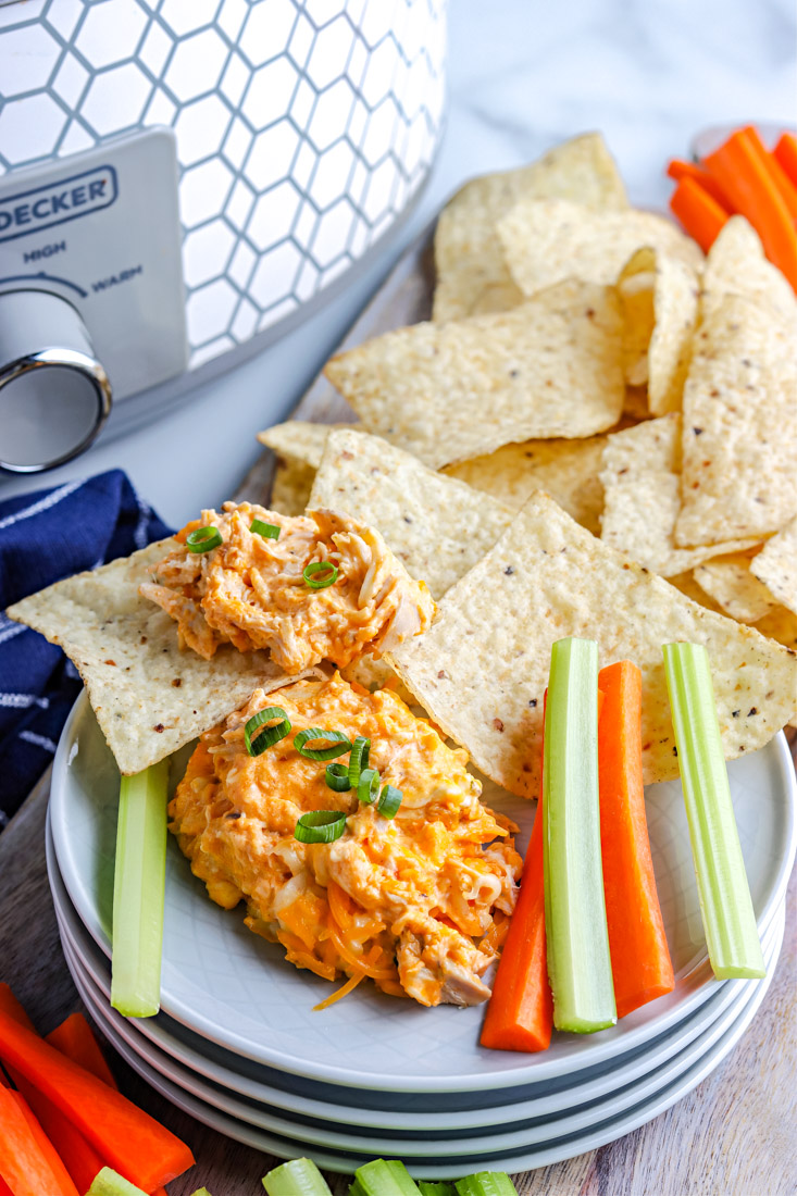 The finished Crockpot Buffalo Chicken Dip on a serving plate with chips, carrots, and celery. 