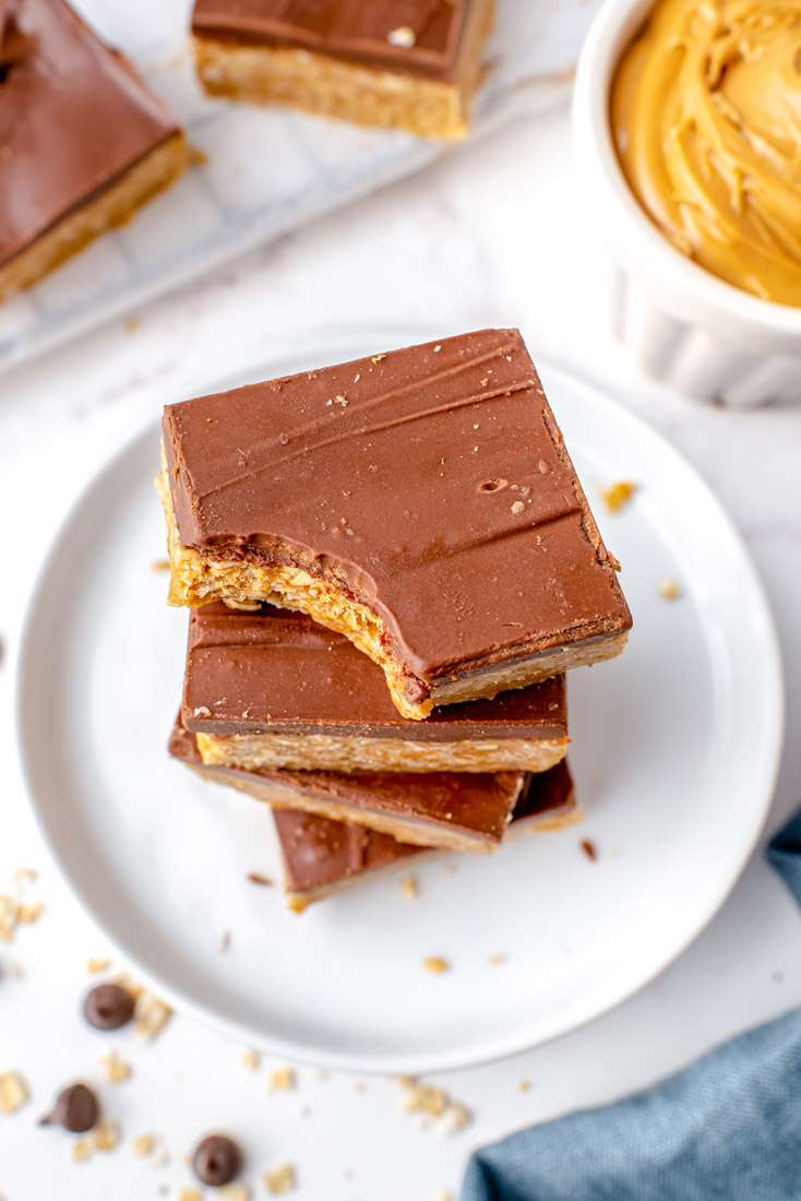 A stack of No-Bake Chocolate Peanut Butter Oatmeal Bars with a bite taken out of the top one.