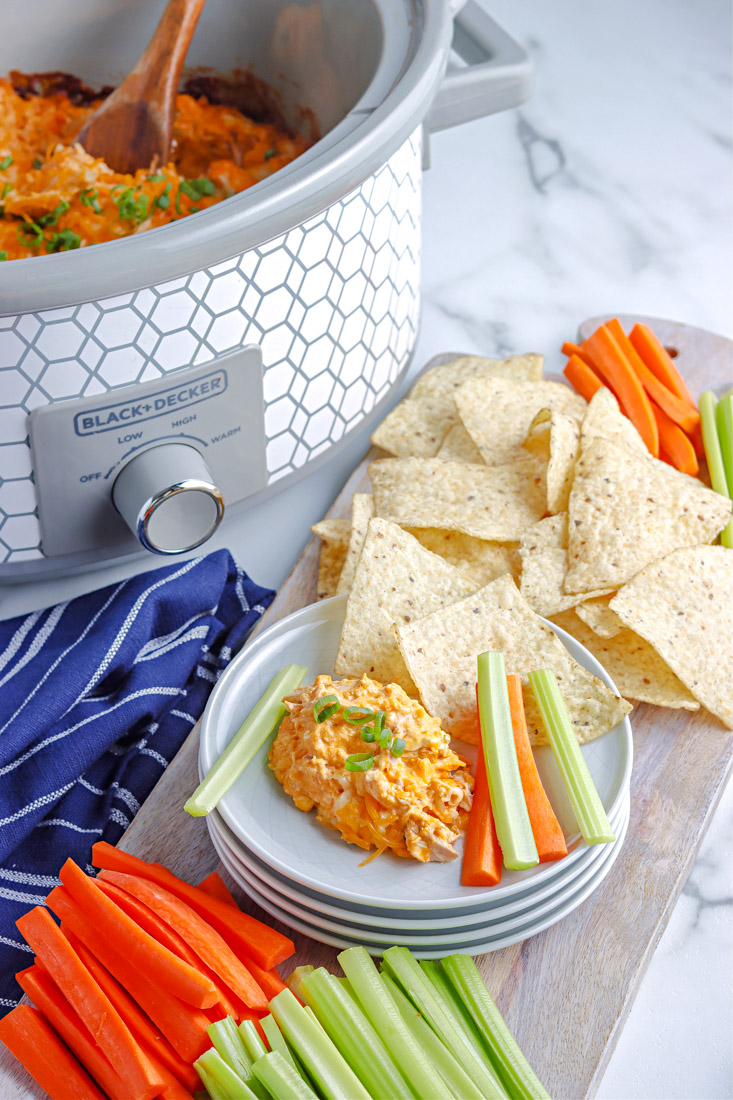 The finished buffalo wing dip in a slow cooker and on a plate.