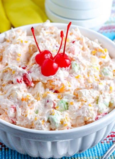 A close up picture of the finished Ambrosia Salad With Cool Whip garnished with cherries.