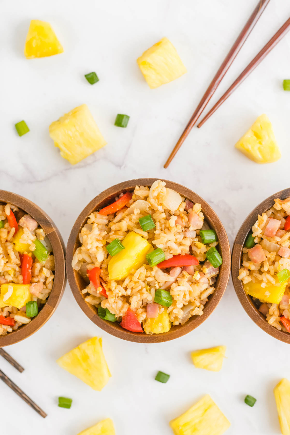 Three wooden bowls full of the fried rice with pineapple.