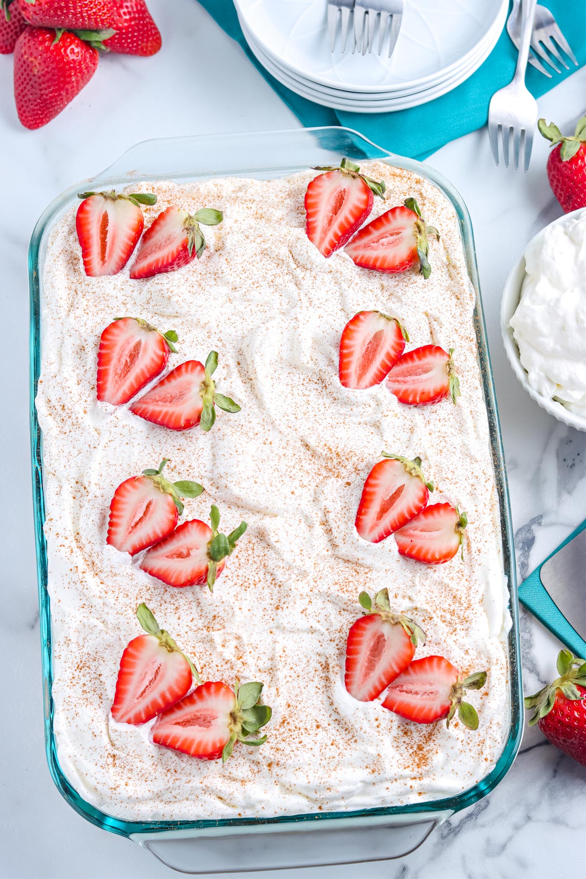 An overhead picture of the finished Tres Leche Cake with strawberries and a sprinkle of cinnamon.