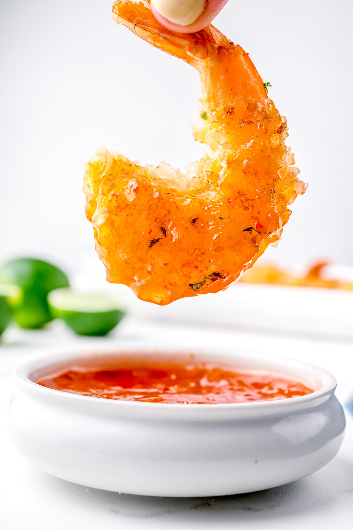 A Coconut Shrimp dipping sauce with a shrimp being dipped into it.