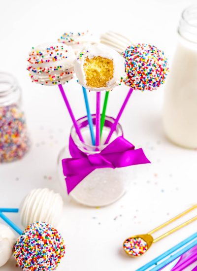 The finished Easy Cake Pops standing upright in a glass jar, one with a bite taken out of it.
