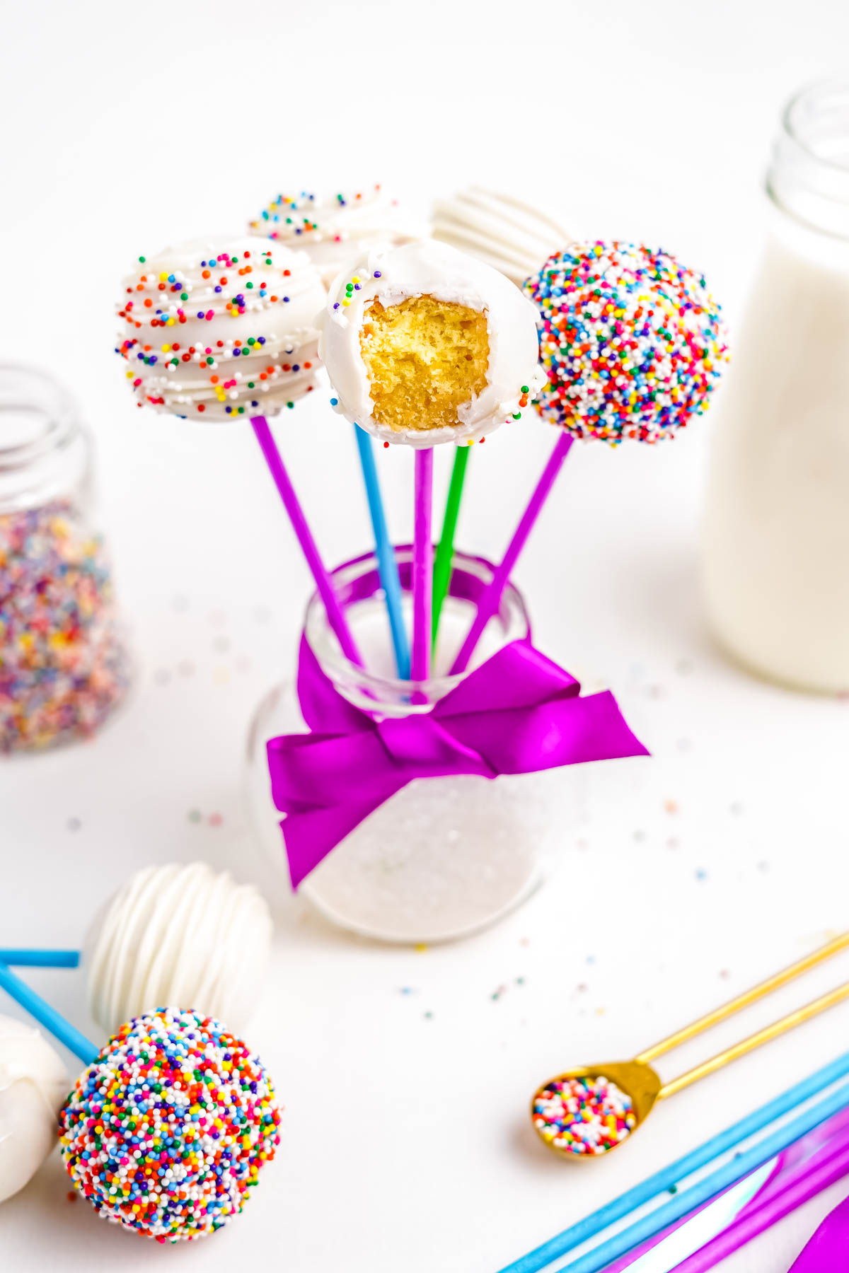 The finished Easy Cake Pops standing upright in a glass jar, one with a bite taken out of it.