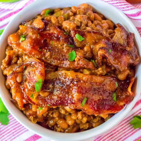 A lose up picture of the finished Loaded Baked Beans recipe in a white serving bowl with bacon on top.