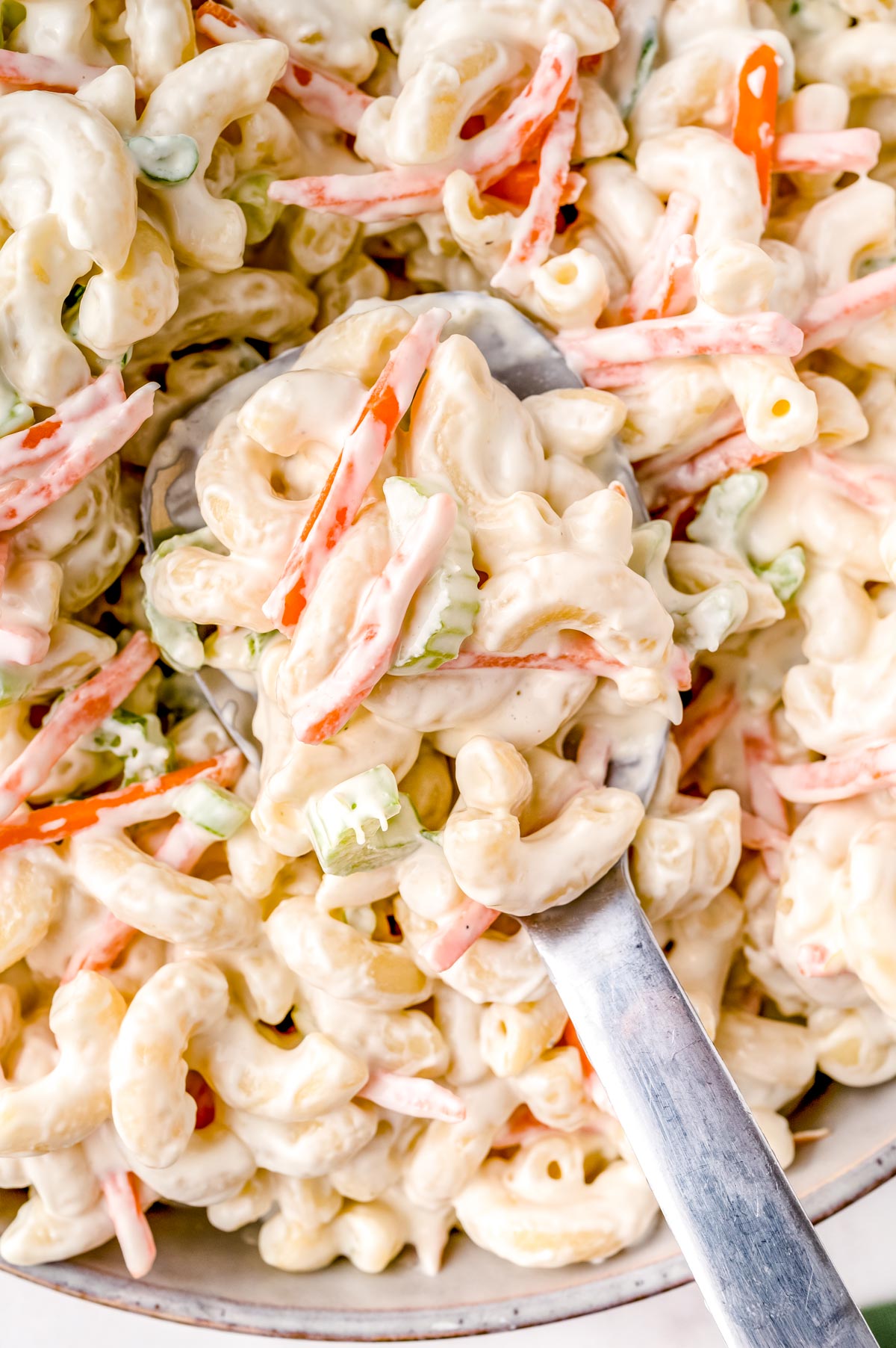 A spoon picking up a coop of the finished Macaroni Hawaiian Salad Recipe.
