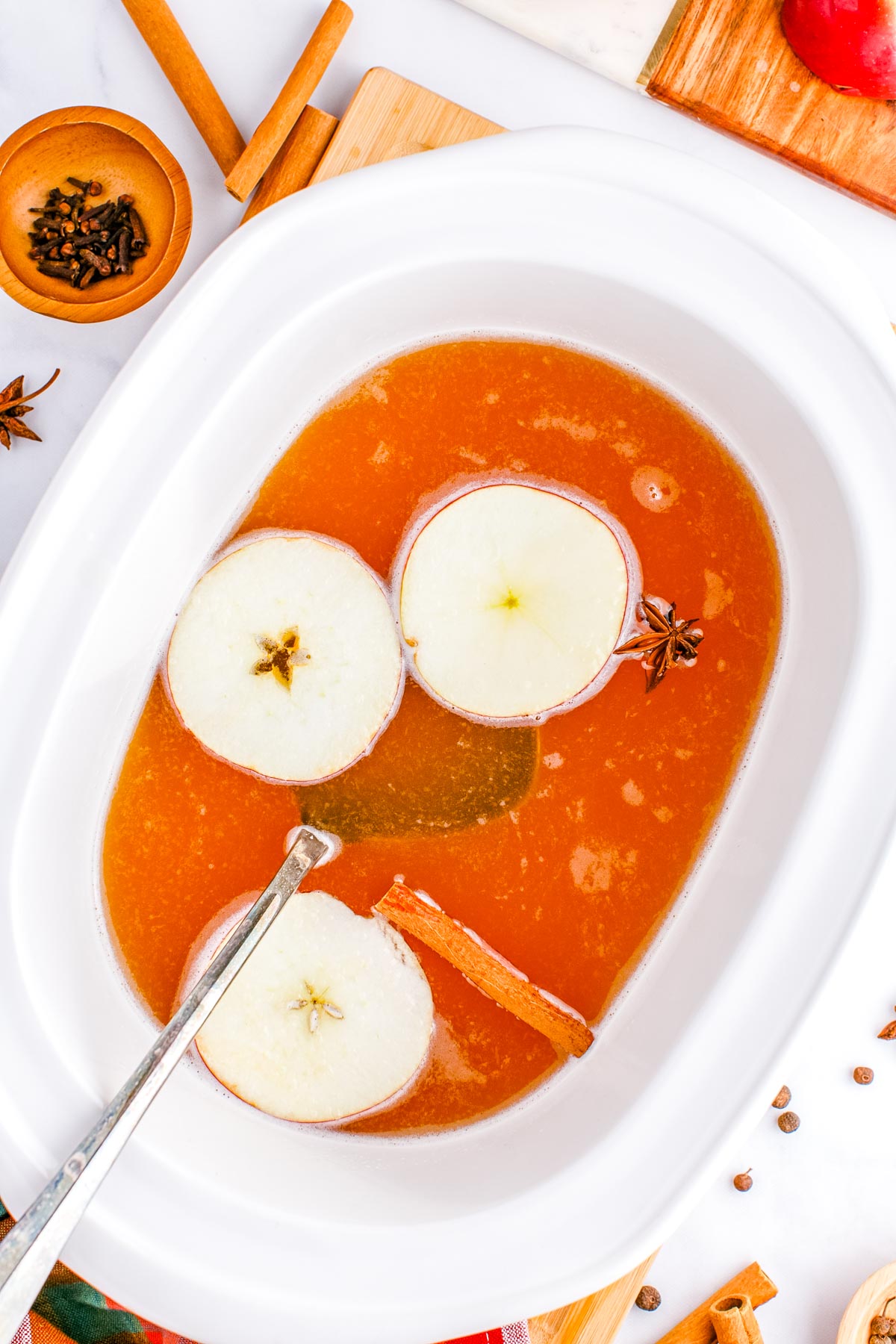 An overhead picture of the finished Slow Cooker Apple Cider with a ladle in the crockpot. 