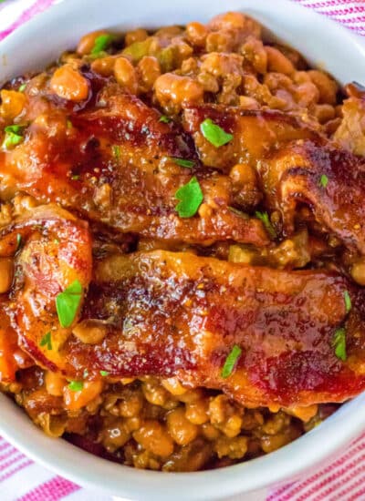 A lose up picture of the finished Loaded Baked Beans recipe in a white serving bowl with bacon on top.