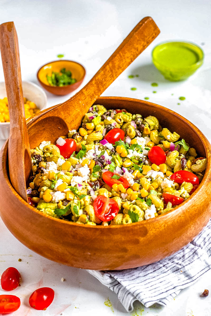 Salad tongs picking up some of the finished Mexican Pasta Salad with corn.