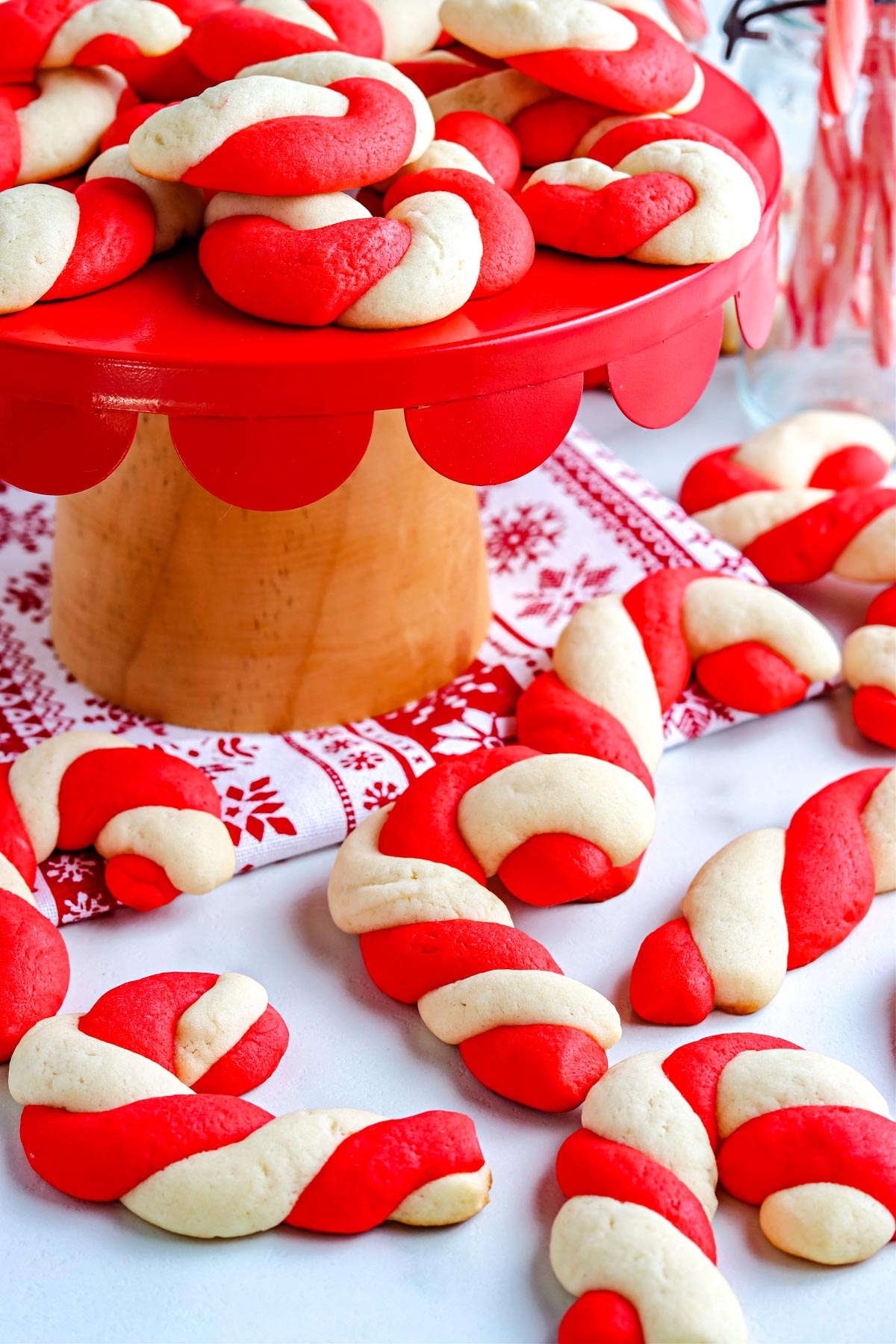 The finished Candy Cane Cookies on a cake stand and on a counter top.