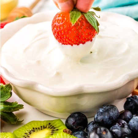 A close up picture of a strawberry being dipped into a Cream Cheese Dip for fruit.