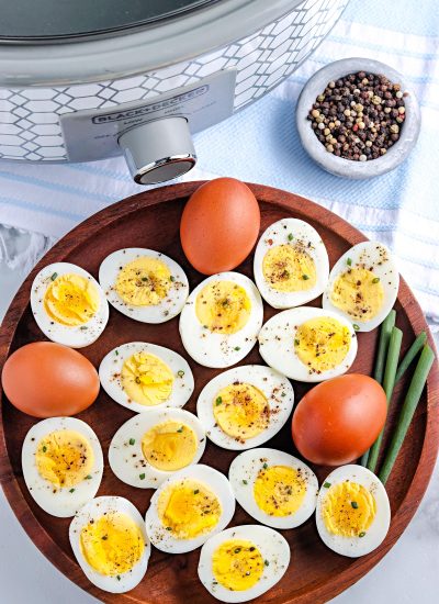 An overhead picture of the finished Crock Pot Hard Boiled Eggs on a wooden platter with the crockpot in the background.