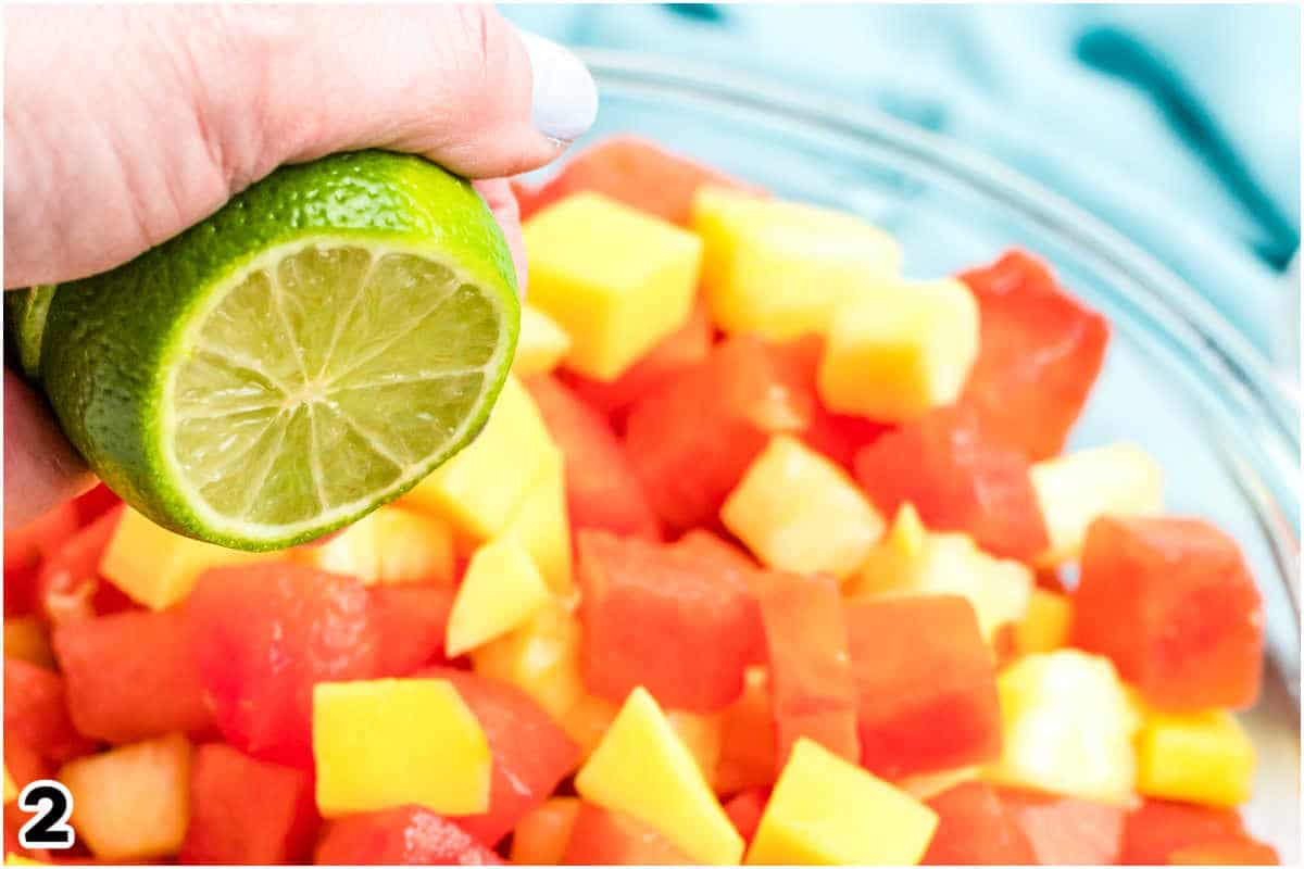 Lime juice being squeezed over fruit salad.