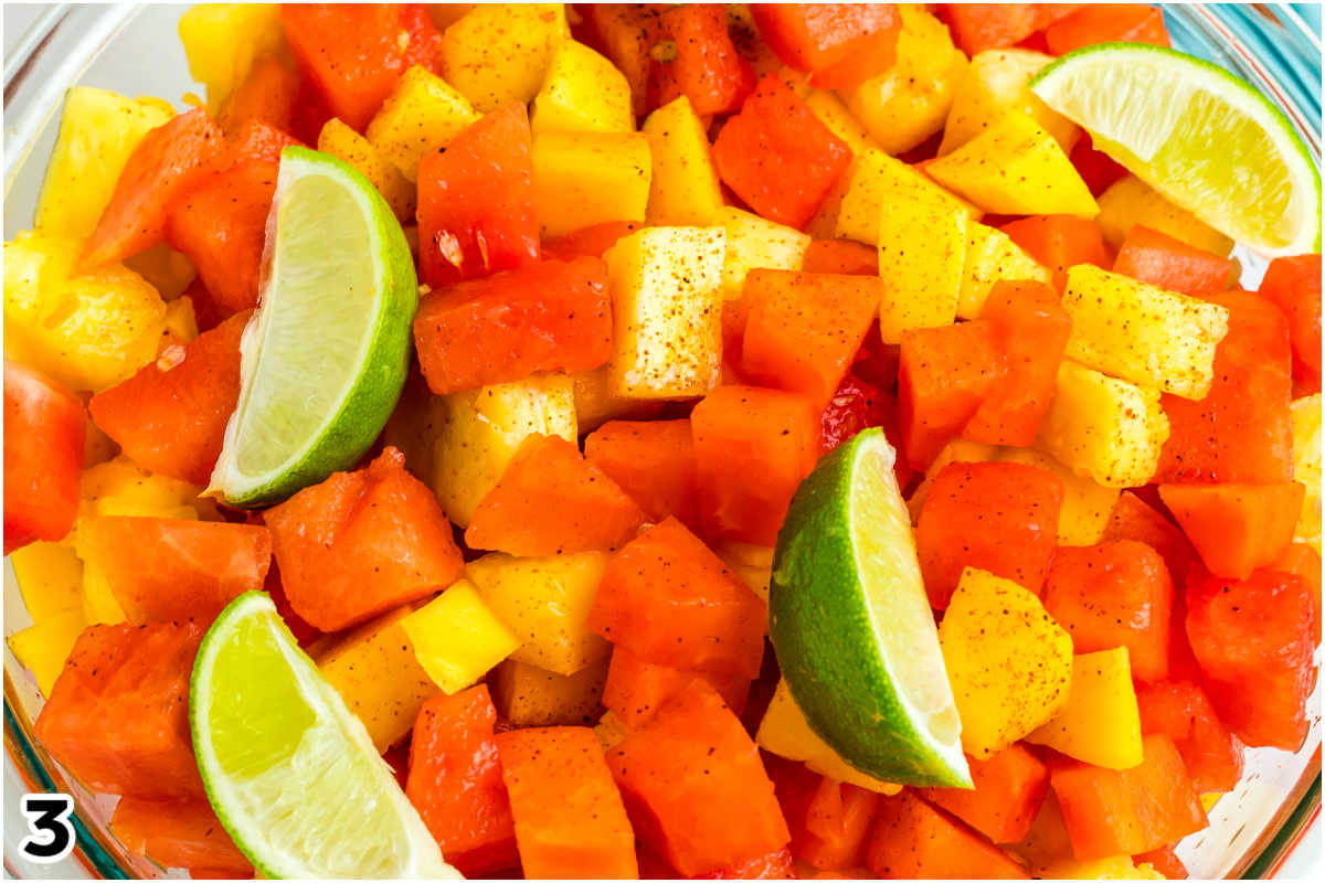 The fruit salad garnished with lime wedges and fresh mint.