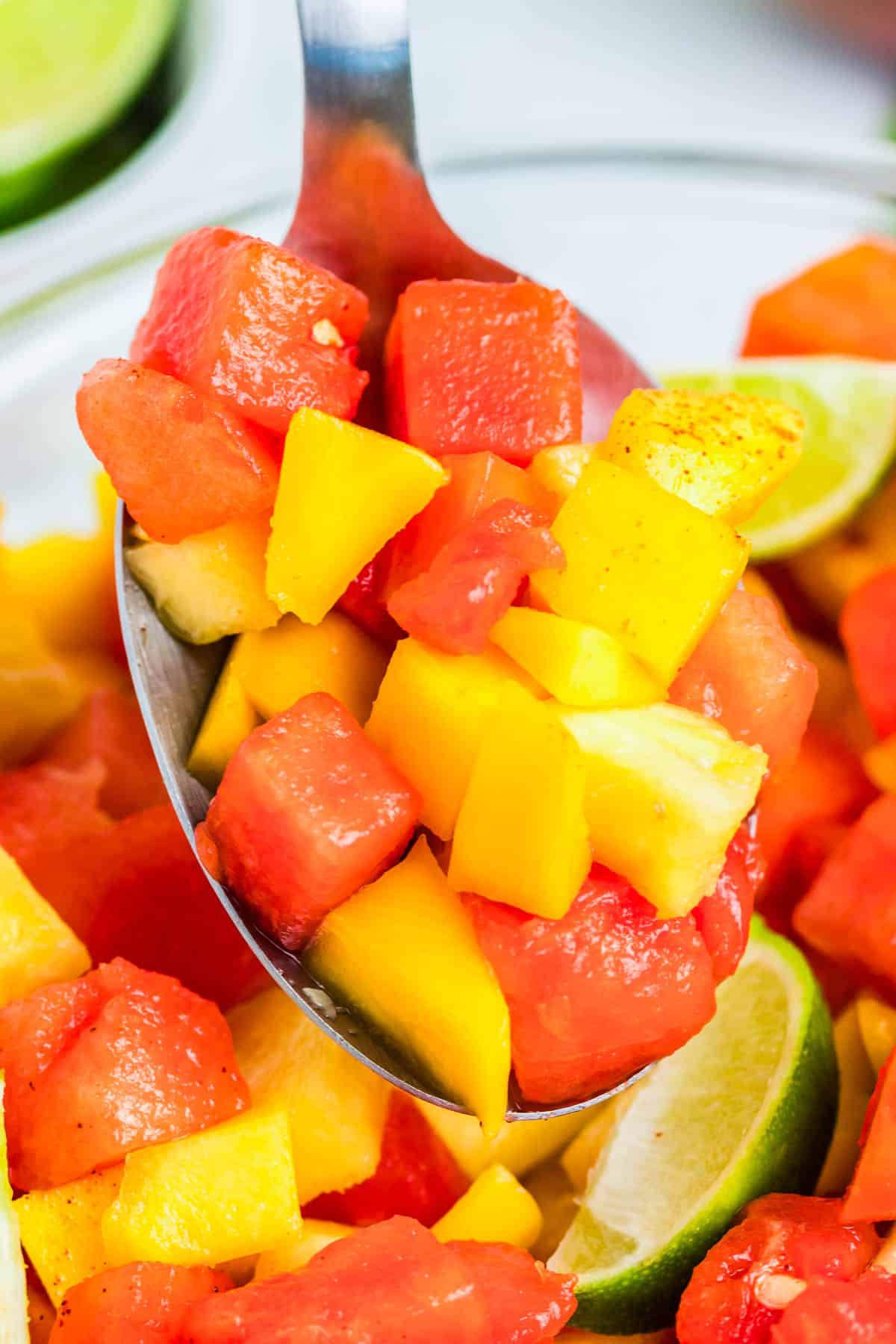 A spoon picking up some Mexican Fruit Salad from a serving bowl.