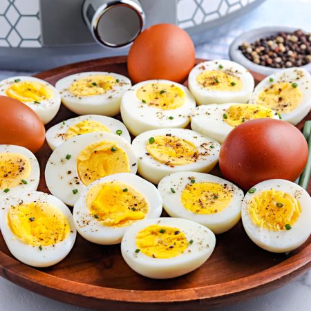 The finished slow cooker hard boiled eggs on a wooden serving platter.