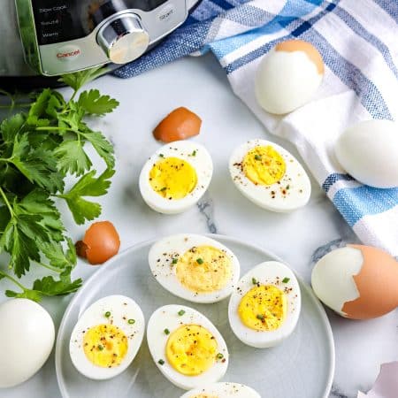 The finished Instant Pot Hard Boiled Eggs on a serving plate with the instant pot in the background.