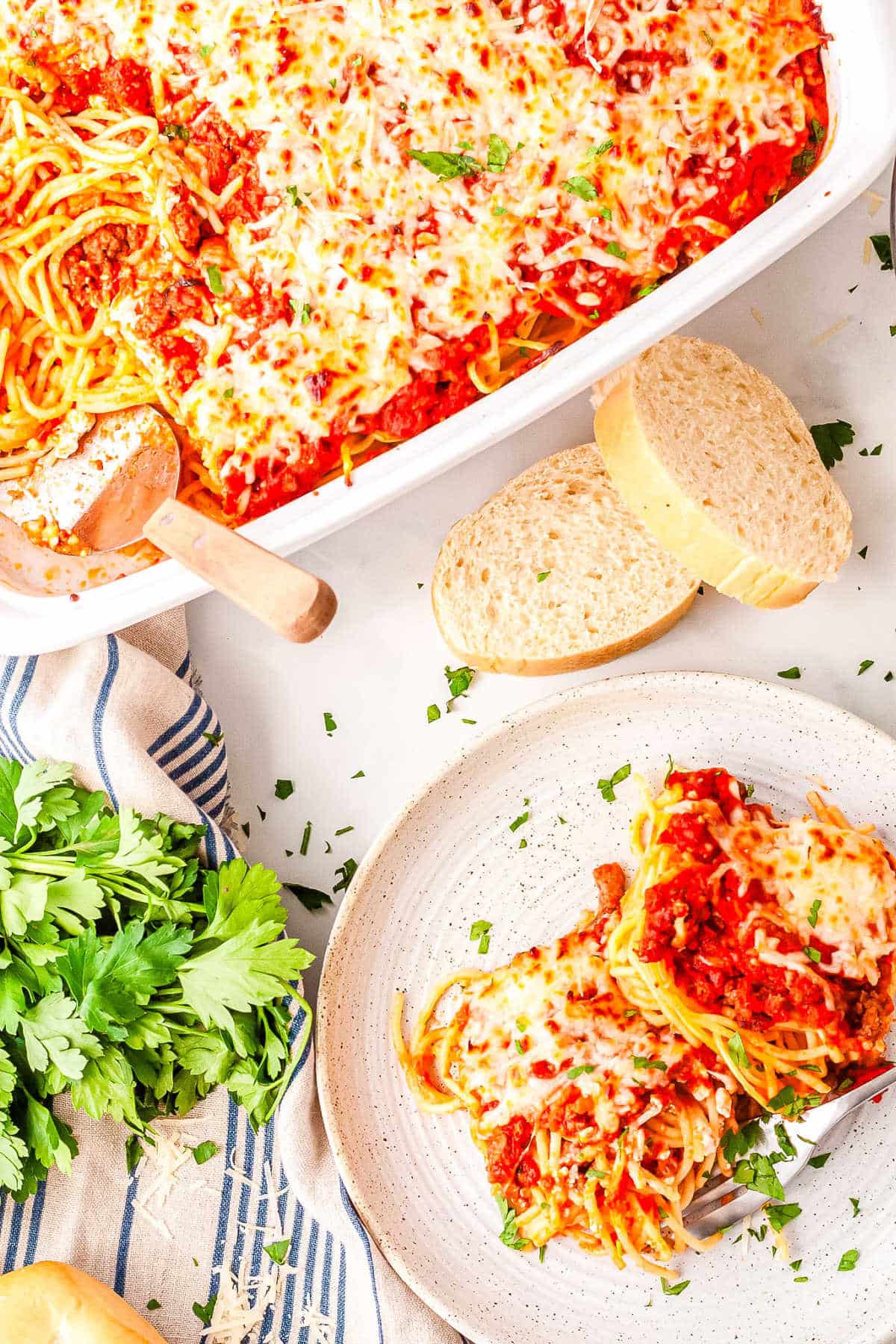 a serving of baked spaghetti on a plate with the casserole dish in the background