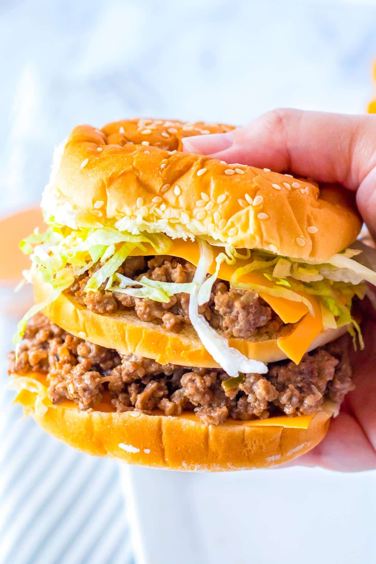 A close up picture of a hand picking up a Big Mac Sloppy Joe. 
