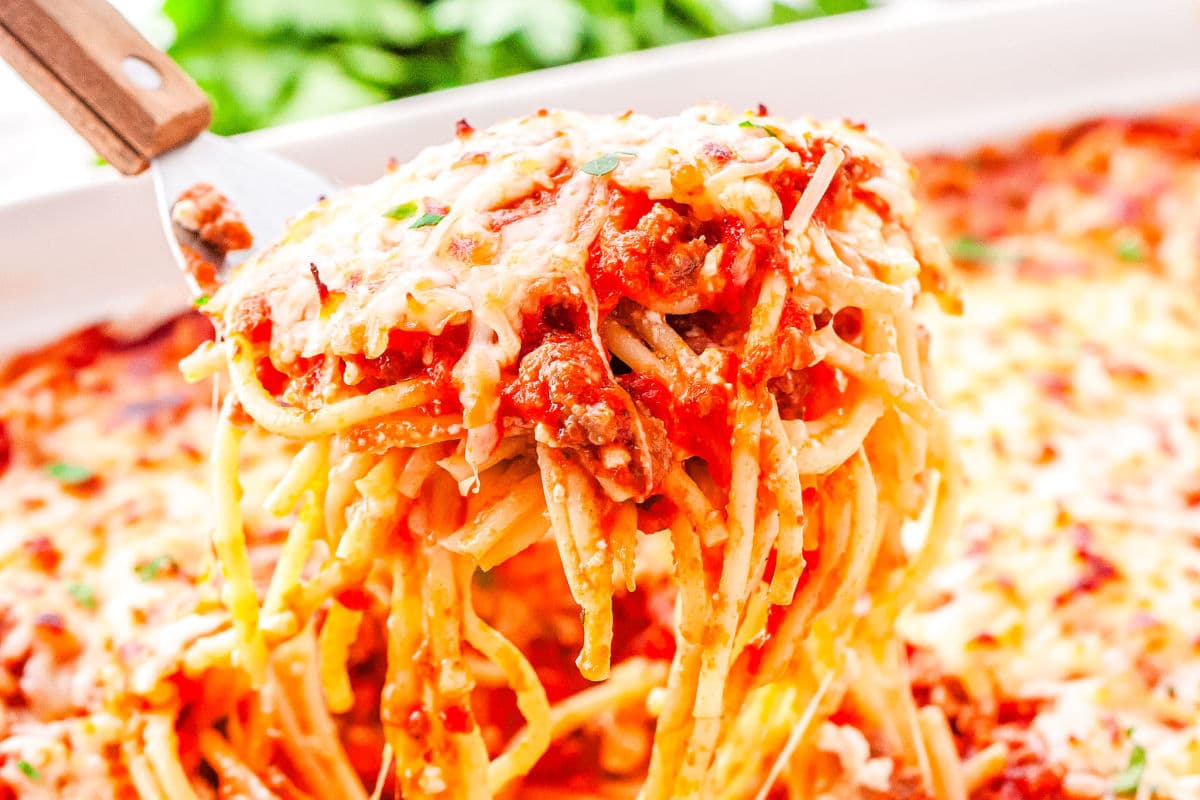 a spatula taking a scoop of baked spaghetti out of a casserole dish