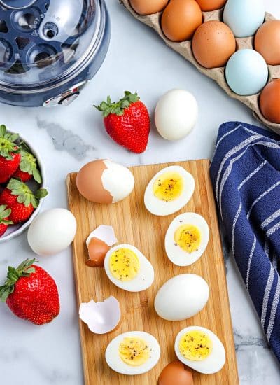 An overhead picture of the finished Egg Cooker Hard Boiled Eggs, peeled and on a wooden cutting board.